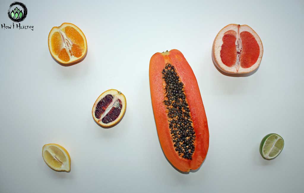 Citrus fruit and papaya halves on a white table.