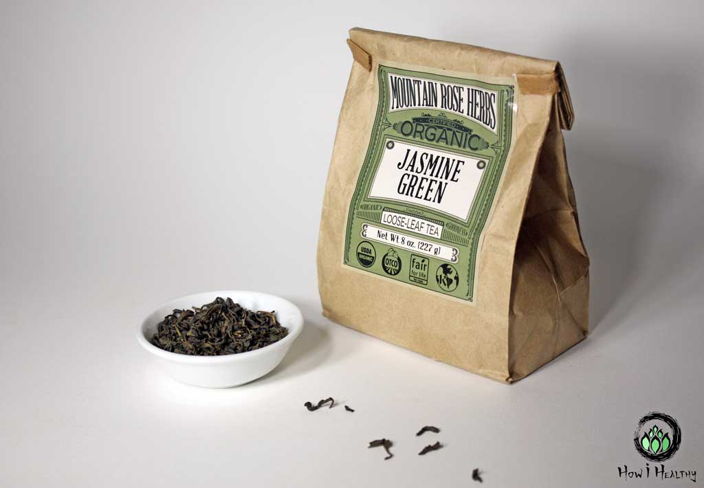 Mountain Rose Herbs® Jasmine green tea leaves in small white dish beside brown bag of tea.