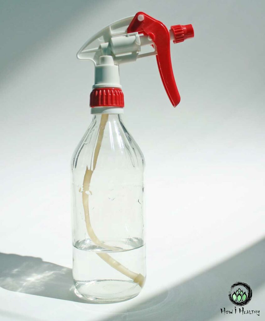 DIY glass spray bottle with red nozzle filled with cleaning solution.