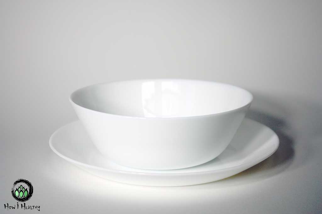 White glass bowl on a white plate.