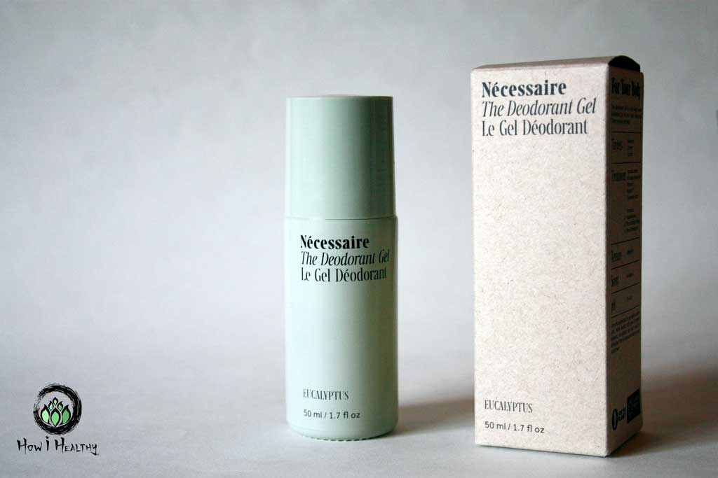 Necessaire glass deodorant bottle beside paper packaging.